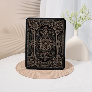 May include: Black tablet case with an ornate gold pattern. The design features swirling floral and scrollwork motifs, creating a vintage or antique aesthetic. The case is rectangular and appears to be made of a durable material.