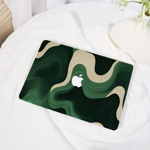 May include: A laptop skin featuring a topographic-inspired pattern of flowing, wavy lines in shades of dark forest green, sage green, and cream. The design creates a layered, depth-filled effect across the surface, centered around the white Apple logo.