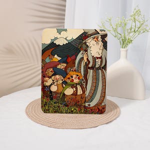 Puede incluir: Una funda rectangular para tableta con una colorida ilustración de un mago alto con una larga barba blanca y un grupo de figuras pequeñas y robustas caminando a través de un campo de flores hacia una cordillera bajo un cielo nublado.