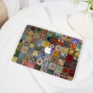 Peut inclure: Une coque d'ordinateur portable avec un motif de mosaïque colorée. Le design intègre divers motifs floraux et géométriques dans des tons de bleu, vert, rouge et jaune. Le logo Apple est visible.