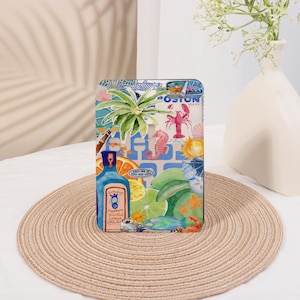 May include: A colourful phone case with a tropical theme. The case features a palm tree, a bottle of gin, a lobster, a seahorse, and a variety of other tropical elements. The text "Call me if you get lost" is printed on the case.