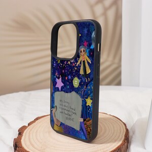 Może przedstawiać: Czarne etui na telefon z kolorową ilustracją rozgwieżdżonego nieba, postacią w ż&oacute;łtym płaszczu i tekstem "Hey Jorney, look what I found. Grandma's trunk. Look familiar? WYBIE".