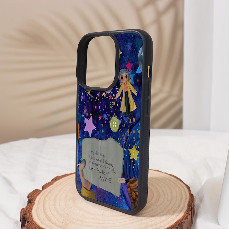 Może przedstawiać: Czarne etui na telefon z kolorową ilustracją rozgwieżdżonego nieba, postacią w ż&oacute;łtym płaszczu i tekstem "Hey Jorney, look what I found. Grandma's trunk. Look familiar? WYBIE".