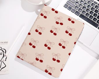 May include: A beige tablet case featuring a repeating pattern of red cherries tied with light pink bows. The case is rectangular and appears to be made of a smooth material. The design is simple and elegant.