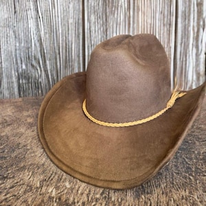 May include: A brown suede cowboy hat with a braided leather band.