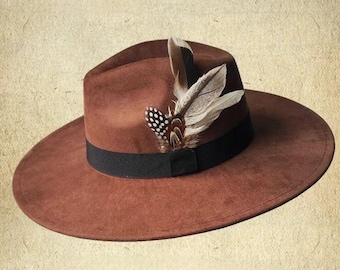 May include: A brown fedora hat with a black band and a feather accent. The feather is brown and white with black spots.