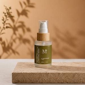 May include: A clear glass serum bottle with a white pump and wooden collar. The label reads "MIFU ORGANICS CLARIFYING SERUM" and includes the text "5% NIACINAMIDE + PHA". The bottle is on a stone surface with a neutral background.