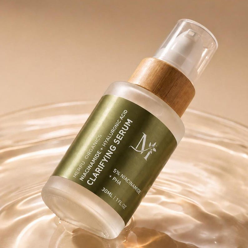 May include: A frosted glass bottle of Merfu Organics Clarifying Serum with a wooden cap. The label is olive green with white text, including "Niacinamide + Hyaluronic Acid" and "5% Niacinamide + PHA". The bottle contains 30ml of serum.