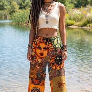 May include: A cream-colored sleeveless crop top with a frayed hem paired with wide-leg pants featuring a vibrant patchwork print of suns, moons, stars, and a cat. The pants have a black drawstring waist and a colorful, multi-patterned design.
