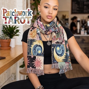 May include: A rectangular scarf featuring a multi-colored patchwork design of tarot card illustrations, including sun and moon motifs with the text The Moon. The scarf has a fringed hem and is worn over a black short-sleeved top and black leggings.