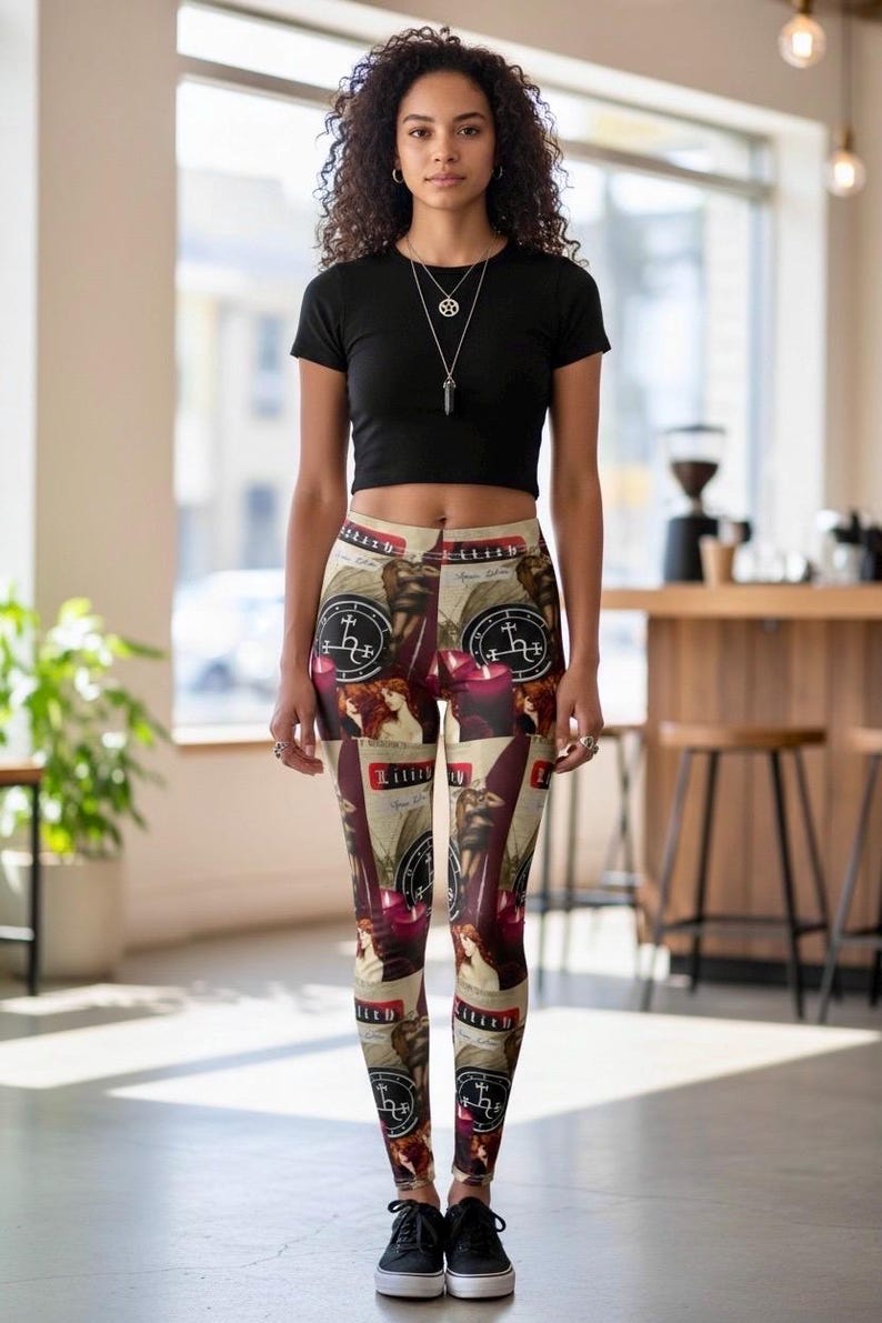 May include: A black short-sleeved crop top and leggings featuring a repeating collage print. The leggings display images of a woman with long red hair, red candles, and circular black symbols with white text reading Lilith and other markings.
