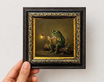 May include: A framed oil painting featuring a green frog wearing round spectacles while reading an open book atop a log. A glowing firefly hovers to the left. The artwork is encased in a dark, ornate frame with gold-toned decorative accents.