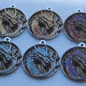May include: Six silver dragon pendant charms with different colored enamel accents. The dragons are in a curled position with their heads facing forward. The charms are approximately 2 inches in diameter.