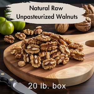 May include: A wooden cutting board displays a pile of raw, unpasteurized walnut halves. The text at the top reads "Natural Raw Unpasteurized Walnuts." The image also shows a knife and some green fruit. The text at the bottom reads "20 lb. box."