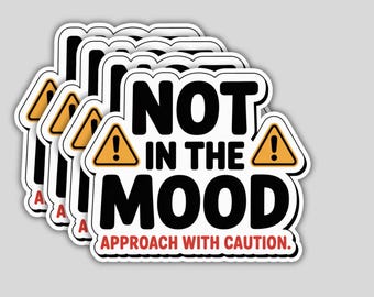 May include: A stack of white stickers with the text "NOT IN THE MOOD" in bold black letters. Each sticker has a yellow hazard symbol with an exclamation point and the words "APPROACH WITH CAUTION" in red.