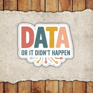 May include: A sticker with the word "DATA" in large, colorful letters: red, teal, gold, and peach. Below, the text reads "OR IT DIDN'T HAPPEN" in a smaller font. The sticker has a white border and a circuit board design at the bottom.