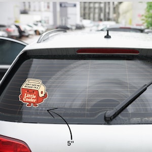 K&ouml;nnte beinhalten: Ein 12,7 cm gro&szlig;er Aufkleber mit einem Cartoon-K&uuml;hler mit dem Text "DON'T HATE ME BECAUSE I'M A Little Cooler". Der K&uuml;hler ist rot mit einem l&auml;chelnden Gesicht und einem Daumen hoch. Der Aufkleber befindet sich auf einem Auto.