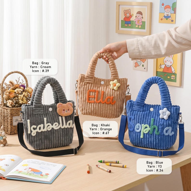 May include: Three corduroy tote bags in gray, khaki, and blue, each with a name embroidered on the front. The gray bag says "Isabella" and has a bear applique. The khaki bag says "Ella" and has a flower applique. The blue bag says "Sophia" and has a flower applique.