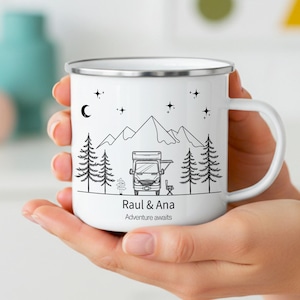 Op de afbeelding: Een witte emaille mok met een zwarte lijntekening van een camper, dennenbomen, bergen, sterren en een maansikkel. De tekst "Raul & Ana" en "Adventure awaits" is in het zwart onder de afbeelding van de camper gedrukt.