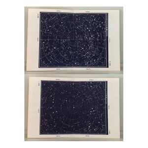 May include: Two open vintage star charts with a dark blue background and white star patterns. The charts are printed on off-white paper and labeled with text. The pages are slightly angled, showing the detailed celestial maps.
