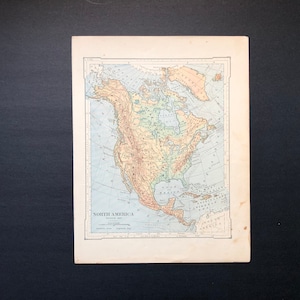 May include: A vintage map of North America with a physical map showing the topography of the continent. The map is printed in shades of blue, green, yellow, and brown. The map is titled "North America Physical Map" and includes a key to the map's symbols.