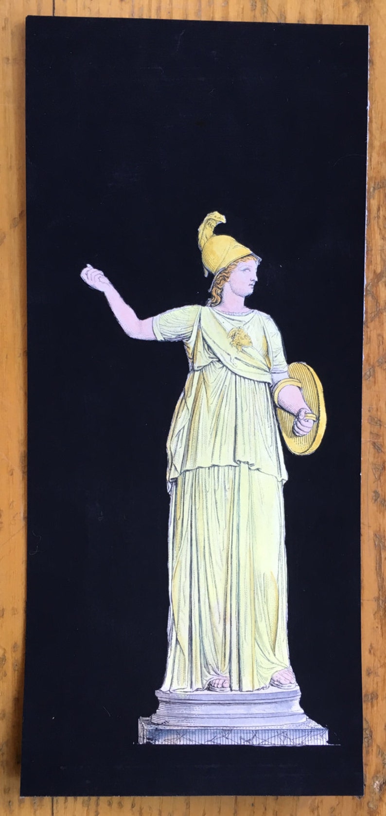 May include: A black and white illustration of a woman wearing a yellow helmet and a yellow dress holding a shield. The woman is standing on a pedestal.
