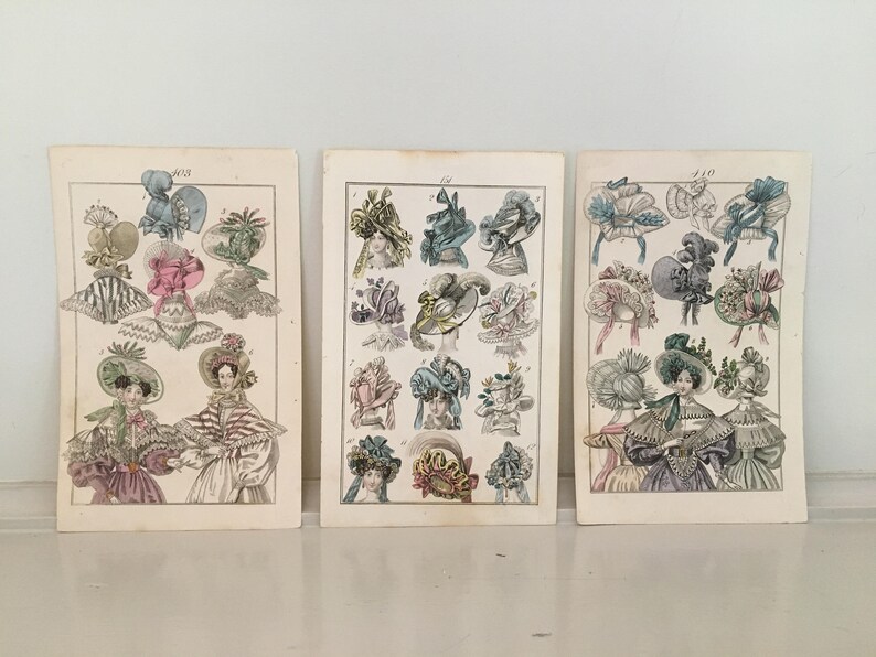 Puede incluir: Tres ilustraciones vintage de mujeres con sombreros elaborados. Las ilustraciones son en blanco y negro con acentos de color pintados a mano. Los sombreros est&aacute;n decorados con flores, cintas y plumas.