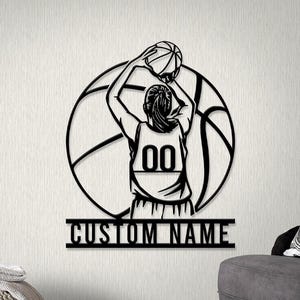 May include: Black metal wall art showing a basketball player shooting a ball, set against a basketball outline. The player wears a jersey with the number 00. The words "CUSTOM NAME" are below the player.