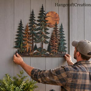 May include: A metal wall art piece featuring a forest of pine trees in shades of green and copper, with a large circular copper sun positioned behind the trees. The artwork displays the text HangcraftCreations in the upper right corner.