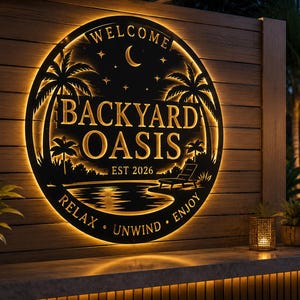 May include: A circular black metal wall sign featuring a backlit design with palm trees, a crescent moon, stars, and a lounge chair. The text reads "WELCOME", "BACKYARD OASIS", "EST 2026", and "RELAX UNWIND ENJOY" in a warm, glowing golden light.