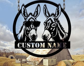 May include: Black metal sign featuring two donkey heads inside a circle, one wearing sunglasses. The sign includes the text "CUSTOM NAME" on a banner below the donkeys. The sign hangs from chains.