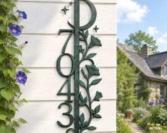 May include: A vertical metal house number sign in a dark green patina finish featuring the numbers 7043, a crescent moon at the top, and a decorative floral vine design with leaves and blossoms running along the right side with small stars.
