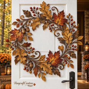 May include: A circular autumn wreath featuring metallic oak leaves in shades of orange, yellow, and brown, accented with clusters of small red berries and brown acorns. The design includes decorative metal scrolls and the text Hangcraft Creations.