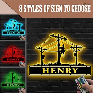 Op de afbeelding: Een zwart metalen bord met een silhouet van een elektricien aan elektriciteitsleidingen, met de naam "HENRY" eronder. Het bord is verlicht in verschillende kleuren, waaronder blauw, rood en groen, en de tekst "8 STYLES OF SIGN TO CHOOSE" staat bovenaan.