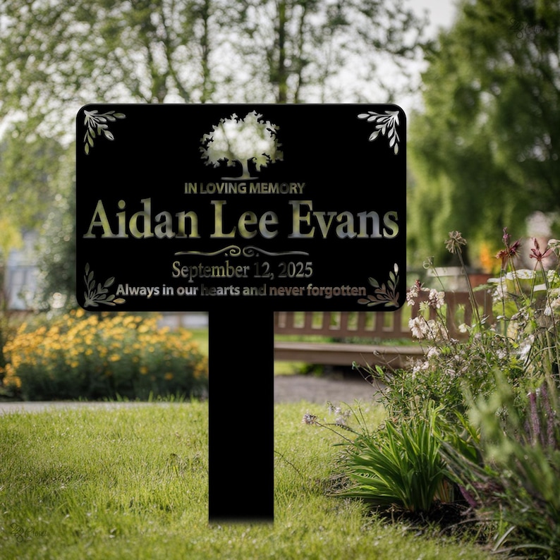 May include: Black metal memorial sign with a tree design and the text "IN LOVING MEMORY Aidan Lee Evans September 12, 2025 Always in our hearts and never forgotten."