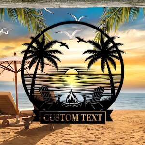 Może przedstawiać: Czarna metalowa grafika ścienna przedstawiająca scenę na plaży z palmami, krzesłami i ogniskiem. Grafika jest okrągła z banerem na dole z napisem "CUSTOM TEXT". Tło przedstawia zachód słońca nad morzem.