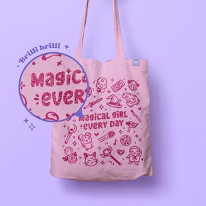 Puede incluir: Bolsa de lona rosa con un diseño de purpurina rosa que dice "Magical girl every day" y presenta una variedad de ilustraciones lindas de artículos de chicas mágicas, incluyendo estrellas, varitas mágicas y un gato.