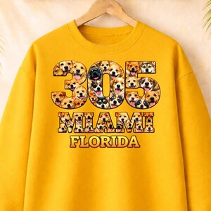 Puede incluir: Una taza de cerámica blanca con un asa negra y el texto "But First, Coffee" en negrita negra. La taza se encuentra sobre un fondo borroso, sugiriendo un ambiente acogedor.