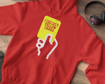 May include: Red hooded sweatshirt with a white graphic of a hand holding a yellow card that says "I collect yellow cards".