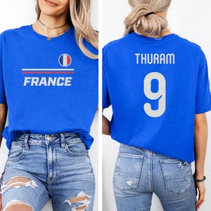 A woman wearing a blue t-shirt with the word "FRANCE" and the number 9 on the back, along with a French flag design.