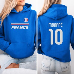 A woman wearing a blue hoodie with the word "FRANCE" printed on it, and the number "10" printed below it.