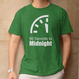 May include: Green t-shirt with the text "90 Seconds to Midnight" in white. The design includes a white graphic resembling a clock face. The shirt is short-sleeved and appears to be made of cotton.
