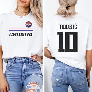 A woman wearing a white t-shirt with the word "Croatia" printed on it, and a number "10" printed on the back. She is also wearing blue jeans.