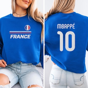 A woman wearing a blue sweatshirt with the word "FRANCE" printed on it, and the number "10" printed on the back.