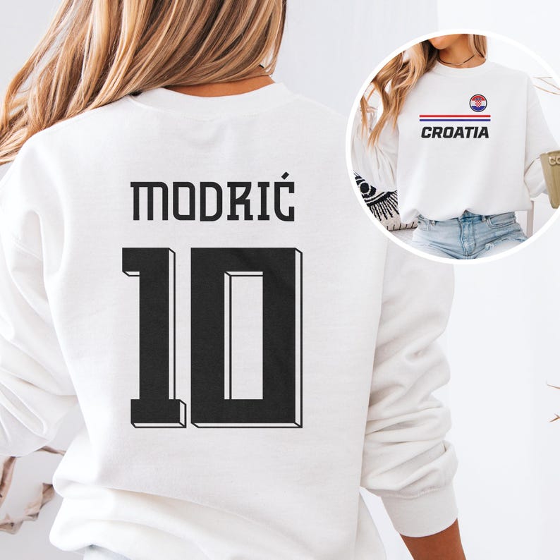 A white sweatshirt with the number 10 and the word "MODRIC" printed on it, along with a graphic of a flag.