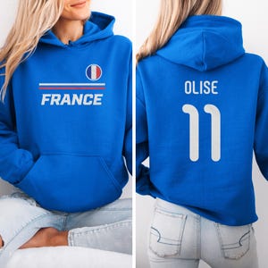 A woman wearing a blue hoodie with the word "FRANCE" printed on it, and the number "11" printed below it.