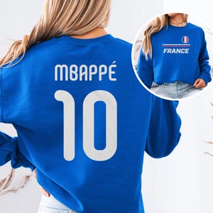 A woman wearing a blue sweatshirt with the number 10 and the word "FRANCE" printed on it.