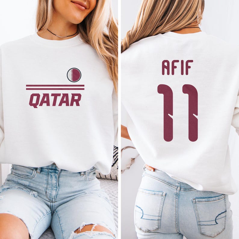 A woman wearing a white sweatshirt with the text "Qatar" and the number "11" printed on it, along with a maroon logo.