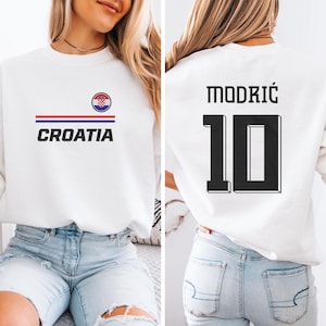 A woman wearing a white sweatshirt with the word "Croatia" printed on it, along with the number 10.