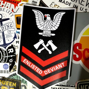 May include: A black and red sticker with a white eagle and crossed axes. The sticker says "Enlisted Deviant" and has the website "HamXDesign.com" at the bottom.